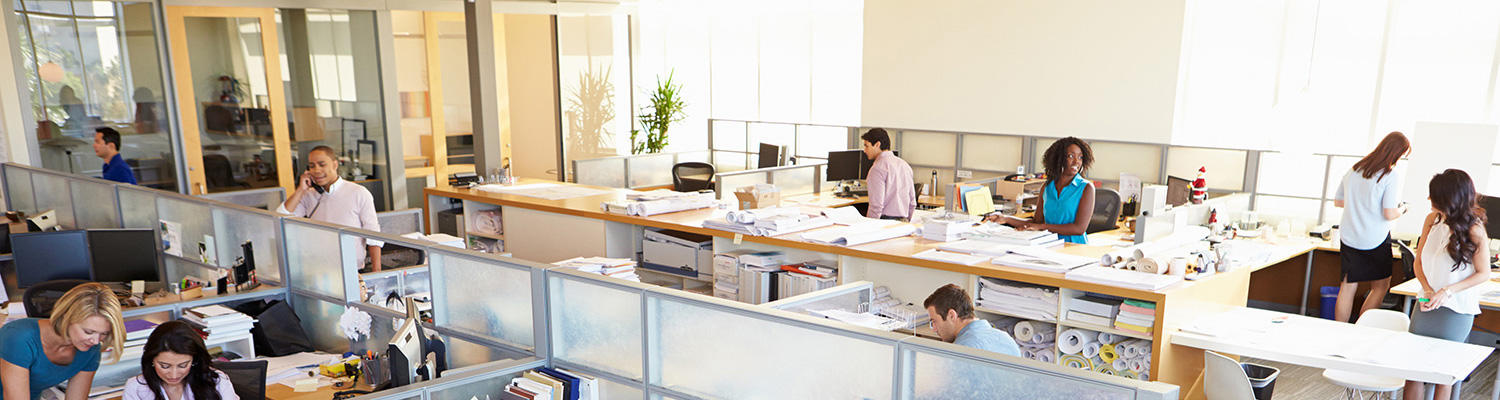 Photo of people working in a busy office setting at desks.