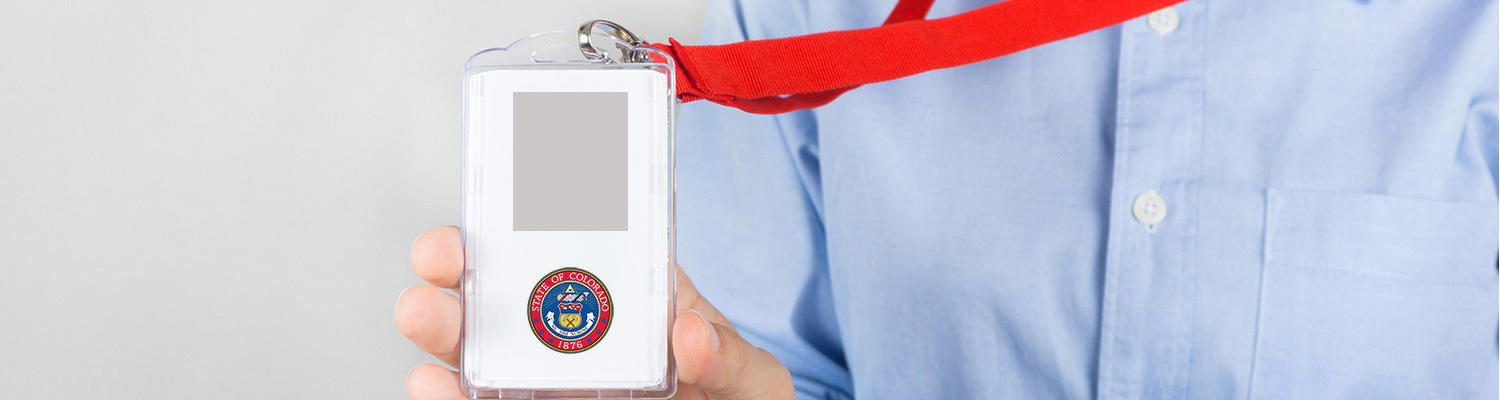 Photo of a person showing an example of an employee ID with the State Seal and a blank rectangle for where the employee photo goes.