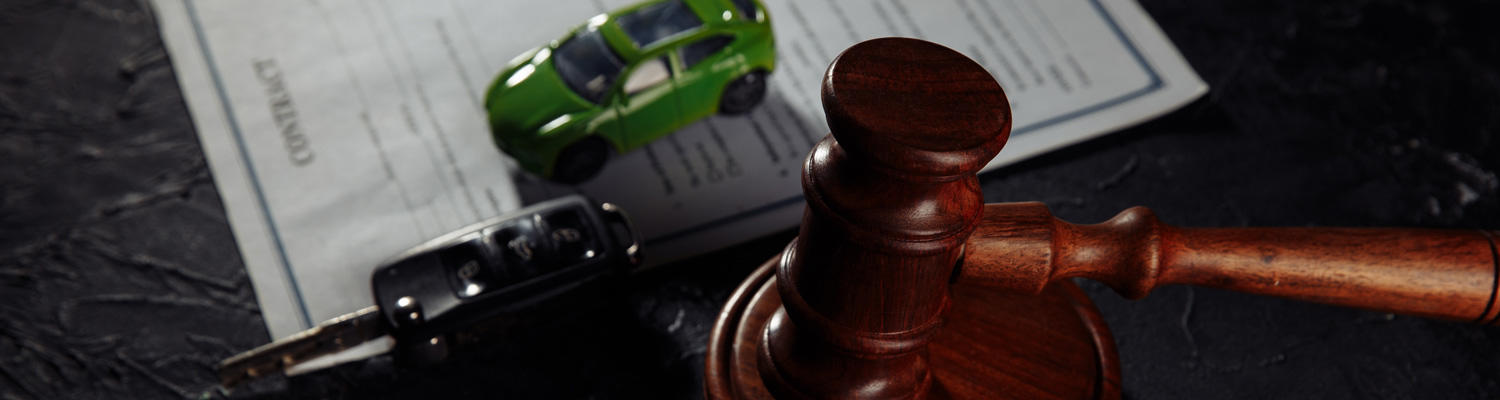 Photo of multiple items on top of a contract that represent vehicle operations contracts showing a key fob, small toy car, and a gavel.