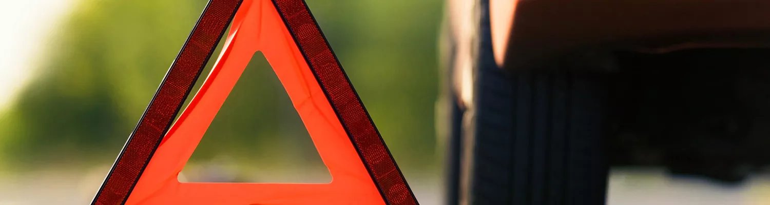 Orange road hazard triangle sign by car tire