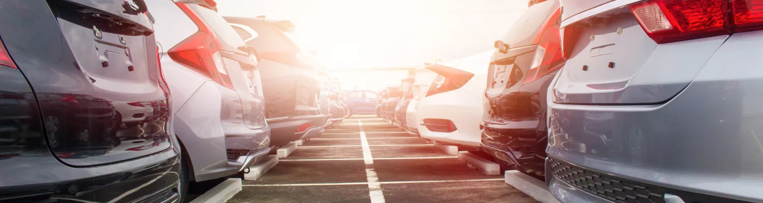 Group of parked cars in a parking lot with sun rays